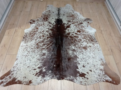 Brązowo-biała skóra bydlęca łaciata rozłożona na jasnej podłodze - dekoracyjneskory.pl