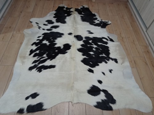 Czarno-kremowa skóra bydlęca łaciata rozłożona na jasnej podłodze - dekoracyjneskory.pl
