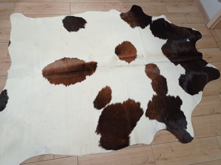 Kremowo-brązowa skóra bydlęca w cętki rozłożona na jasnej podłodze - dekoracyjneskory.pl