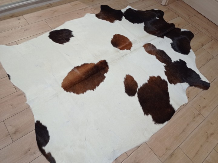 Kremowo-brązowa skóra bydlęca w cętki rozłożona na jasnej podłodze - dekoracyjneskory.pl