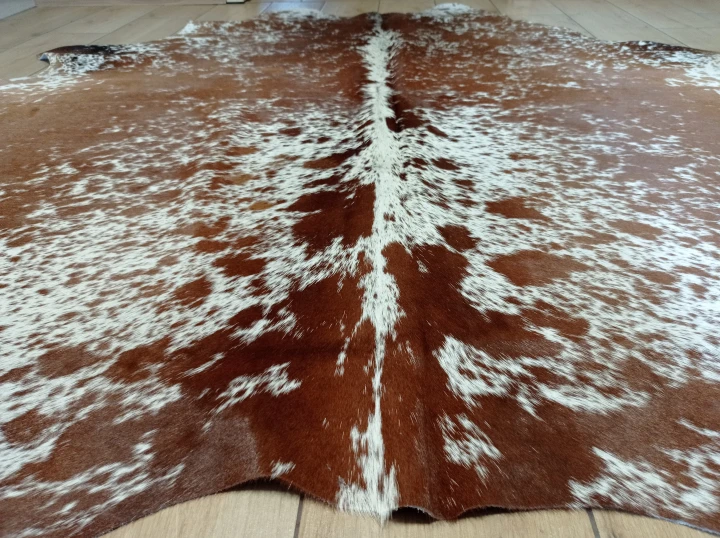 Naturalna skóra bydlęca ŁACIATA 195x195 cm rozłożona w dużym salonie  - zbliżenie na lśniący włos - dekoracyjneskory.pl