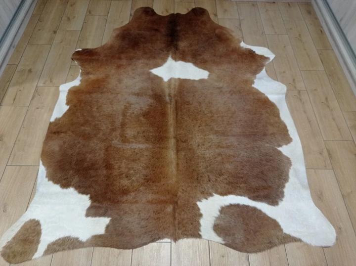 Naturalna skóra bydlęca brązowo-biała 200x165 cm rozłożona w dużym salonie  - dekoracyjneskory.pl