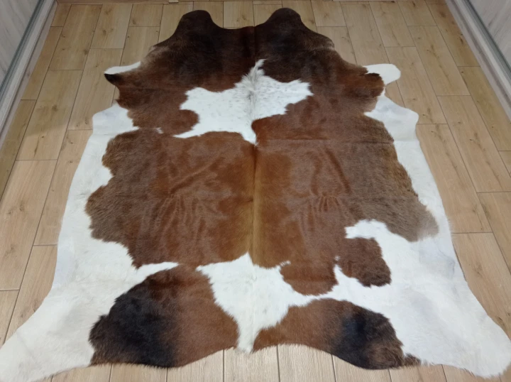 Naturalna skóra bydlęca BRĄZOWO-BIAŁA 205x180 cm rozłożona w dużym salonie  - dekoracyjneskory.pl