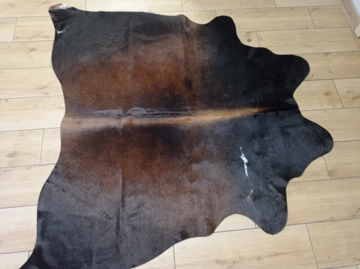 Naturalna skóra bydlęca BRĄZOWO-CZARNA 145x155 cm rozłożona w dużym salonie  - dekoracyjneskory.pl