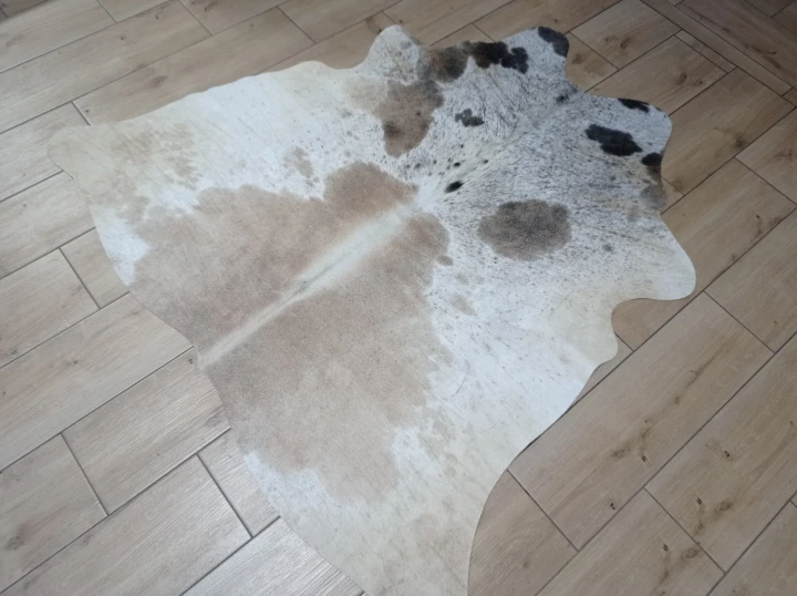Naturalna skóra bydlęca ŁACIATA BEŻOWO-BRĄZOWA 130x140 cm rozłożona w dużym salonie  - dekoracyjneskory.pl