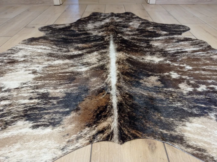 Naturalna skóra bydlęca TYGRYS BRĄZOWO-BEŻOWY 140x130 cm rozłożona w dużym salonie  - zbliżenie na lśniący włos - dekoracyjneskory.pl